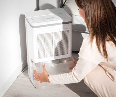 A Woman Removing The Water Container Of Her Dehumidifier How Often Do Dehumidifiers Need to Be Emptied
