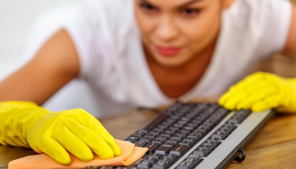 Closeup of a Woman Wearing Yellow Cleaning Gloves Wiping a Keyboard How Do You Know if an Item Can Be Disinfected