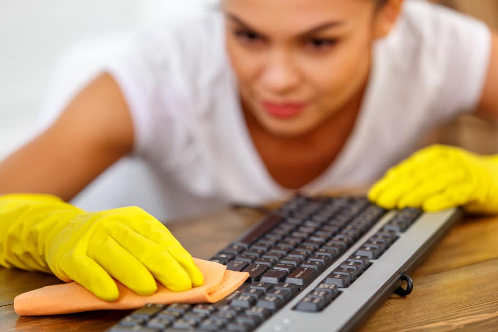 Closeup of a Woman Wearing Yellow Cleaning Gloves Wiping a Keyboard How Do You Know if an Item Can Be Disinfected
