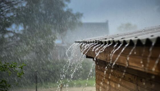 Closeup of a House’s Roof With Heavy Rain Trickling off It Prepare Your Home for Summer Storms
