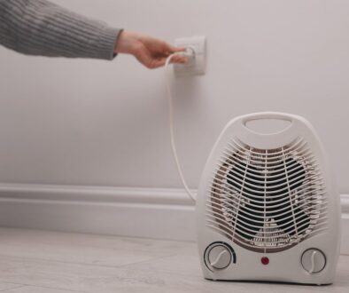 Closeup Of A Space Heater Sitting On The Ground With A Person Unplugging It From A Wall Outlet Space Heater Fire Safety Tips