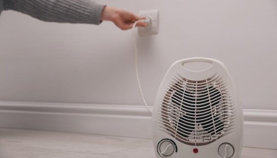 Closeup Of A Space Heater Sitting On The Ground With A Person Unplugging It From A Wall Outlet Space Heater Fire Safety Tips